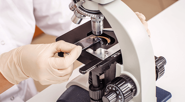man using microscope on a sample